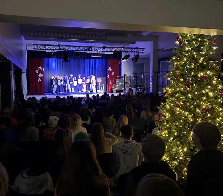 En gruppe mennesker i et rom med et juletre og en scene