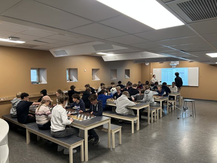 en gruppe mennesker som sitter ved bord i et rom med en projektorskjerm en gruppe mennesker som sitter ved bord i et rom med en projektorskjerm